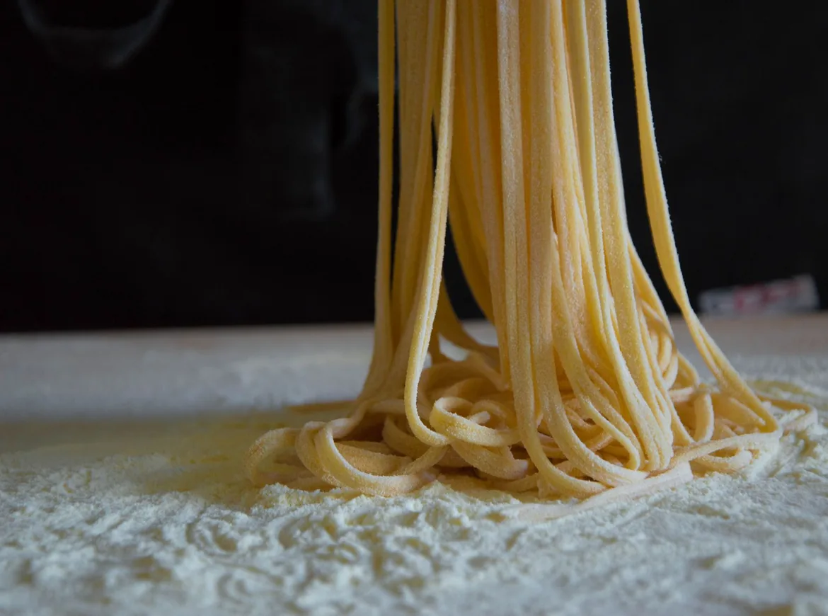 Strands of fresh pasta piled on a flour-dusted board